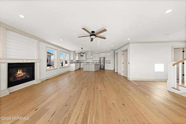 unfurnished living room with ceiling fan, ornamental molding, and light hardwood / wood-style floors