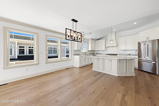 kitchen with custom exhaust hood, a kitchen island, high end fridge, and white cabinets