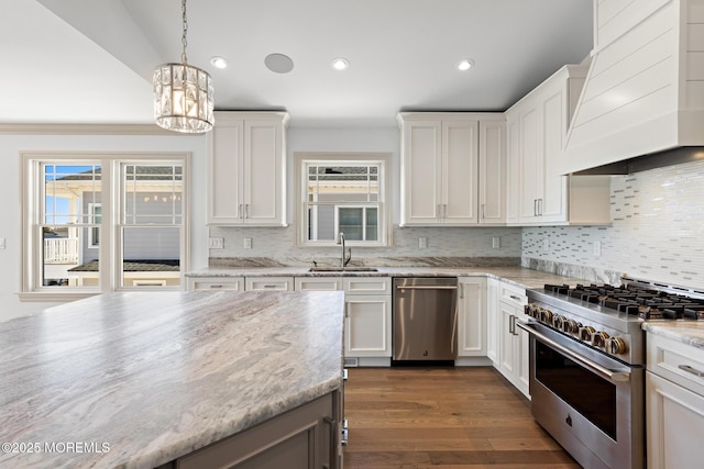 kitchen with sink, premium range hood, stainless steel appliances, light stone countertops, and white cabinets