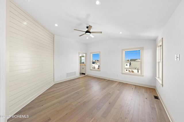 unfurnished living room with ceiling fan, a healthy amount of sunlight, vaulted ceiling, and light hardwood / wood-style flooring