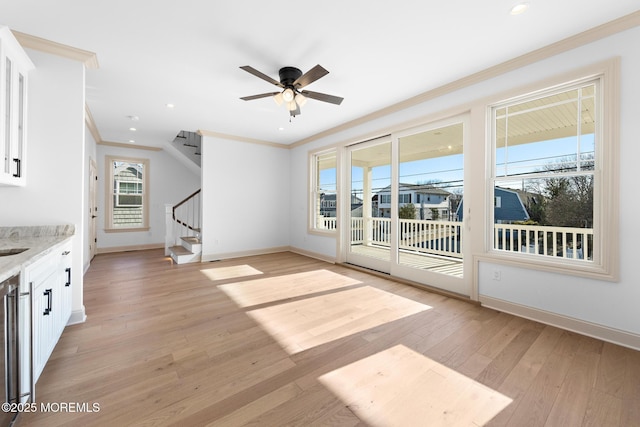 unfurnished living room with ceiling fan, ornamental molding, and light hardwood / wood-style flooring