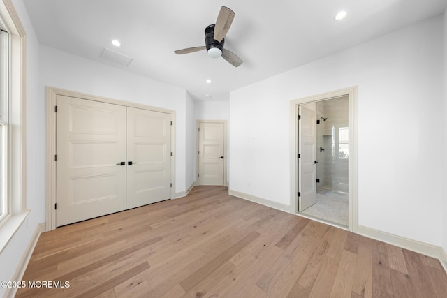 unfurnished bedroom featuring ceiling fan, ensuite bathroom, light hardwood / wood-style floors, and a closet