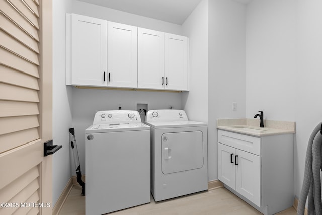 laundry area featuring cabinets, separate washer and dryer, sink, and light wood-type flooring