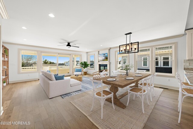 dining space featuring ornamental molding, ceiling fan with notable chandelier, and light hardwood / wood-style floors