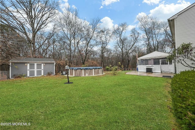 view of yard featuring a patio, a covered pool, and a storage unit