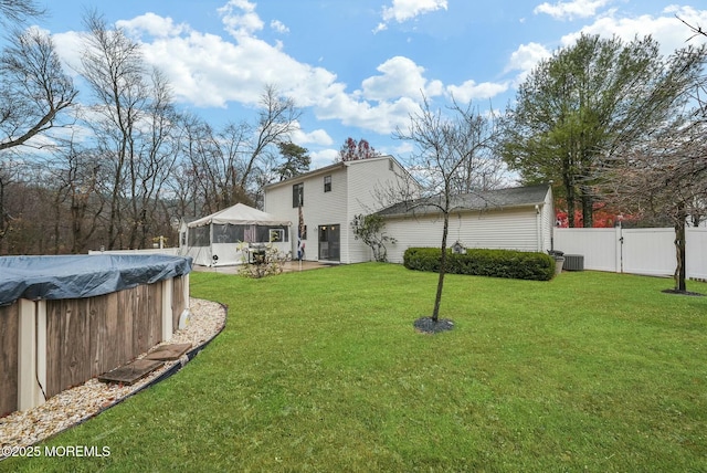 back of house featuring cooling unit, a gazebo, a lawn, and a covered pool