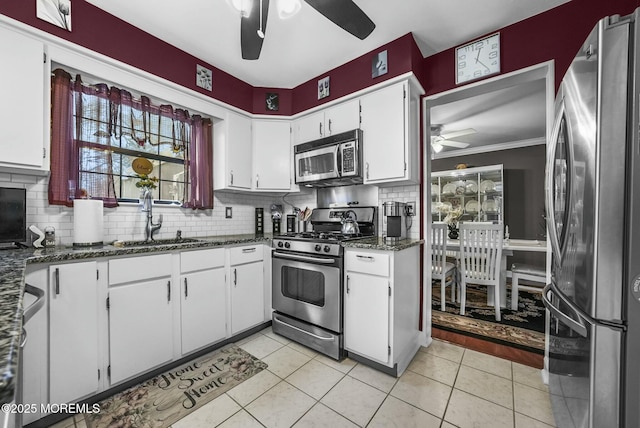 kitchen with appliances with stainless steel finishes, dark stone countertops, white cabinets, and ceiling fan