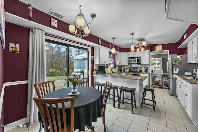 kitchen featuring pendant lighting, stainless steel appliances, dark stone counters, and white cabinets