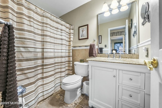 bathroom featuring tile walls, vanity, and toilet