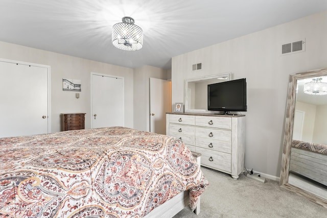 bedroom with light carpet and two closets