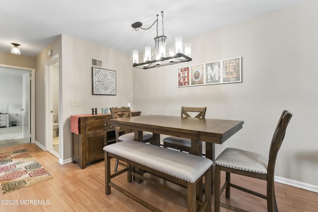 dining space with an inviting chandelier and light wood-type flooring