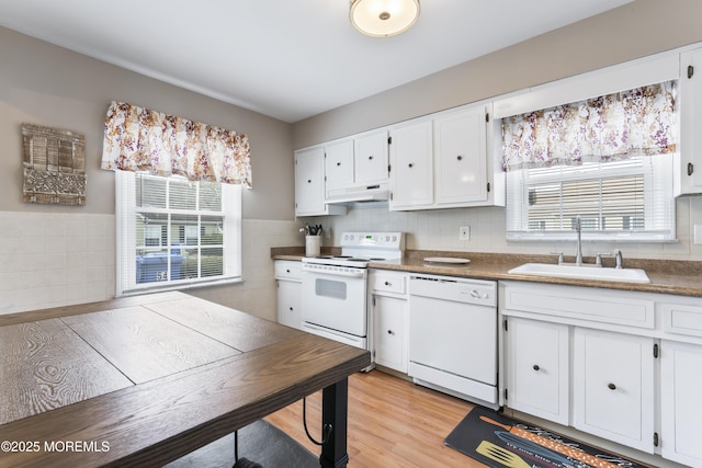 kitchen featuring a healthy amount of sunlight, sink, white cabinets, and white appliances