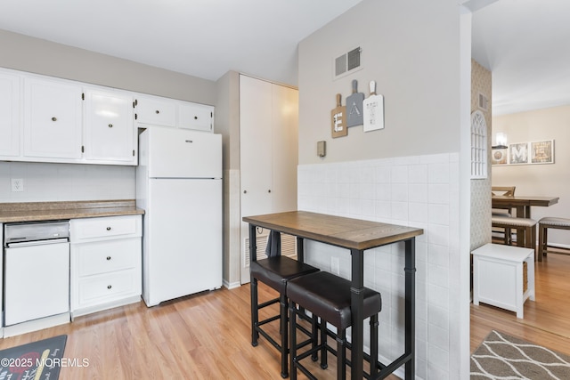 kitchen featuring white cabinetry, light wood-type flooring, and white fridge