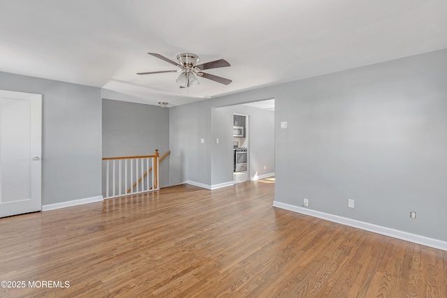 empty room featuring ceiling fan, baseboards, and wood finished floors