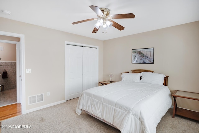 bedroom with ceiling fan, light colored carpet, and a closet