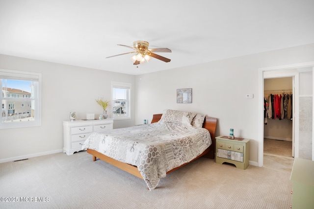 carpeted bedroom with a walk in closet, a closet, and ceiling fan