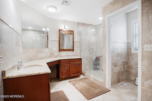 bathroom featuring vanity, tile walls, and a shower with shower door