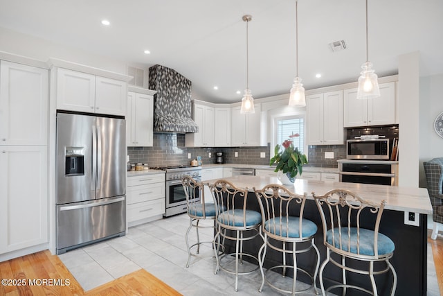 kitchen featuring appliances with stainless steel finishes, decorative light fixtures, a kitchen island, and white cabinets