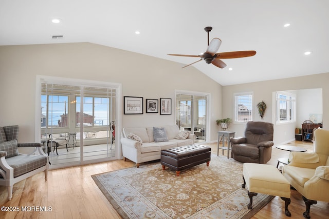 living room with light wood-type flooring, ceiling fan, vaulted ceiling, and a wealth of natural light