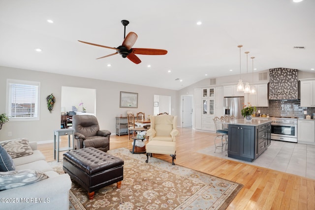 living room featuring ceiling fan, lofted ceiling, and light hardwood / wood-style floors