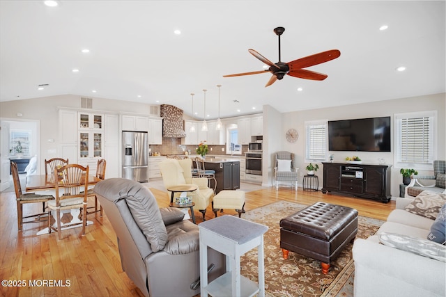 living room featuring ceiling fan, light hardwood / wood-style floors, and vaulted ceiling