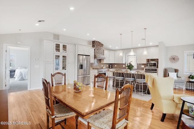 dining space featuring lofted ceiling, light hardwood / wood-style flooring, and a wealth of natural light