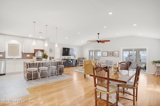 dining room with ceiling fan, lofted ceiling, sink, and light hardwood / wood-style flooring