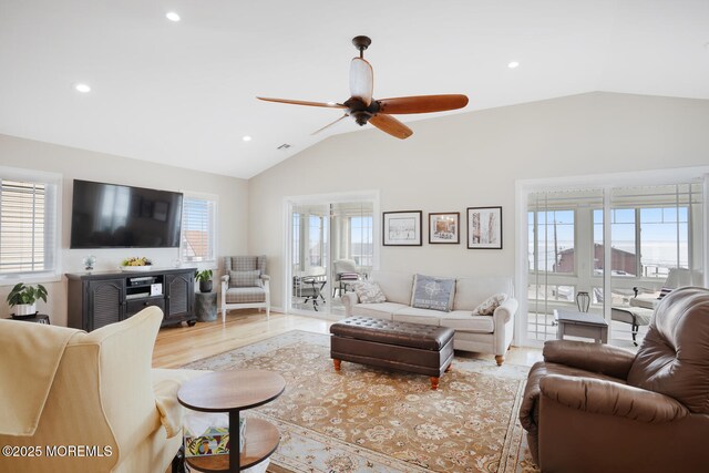 living room featuring ceiling fan, light hardwood / wood-style floors, vaulted ceiling, and a wealth of natural light