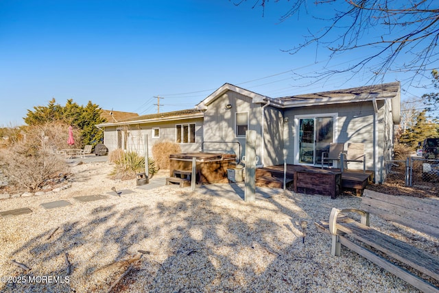 rear view of property featuring a hot tub and a patio area