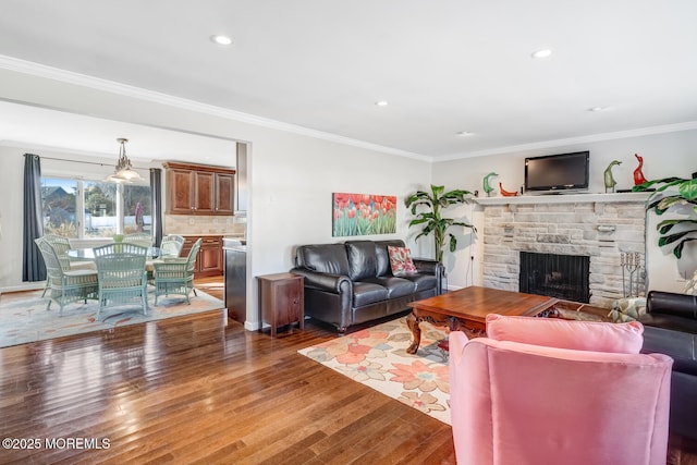 living room with a fireplace, crown molding, and dark wood-type flooring