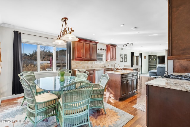 dining space featuring sink, ornamental molding, and light hardwood / wood-style floors