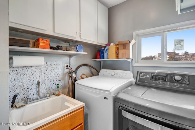 laundry room with cabinets, washer and clothes dryer, and sink