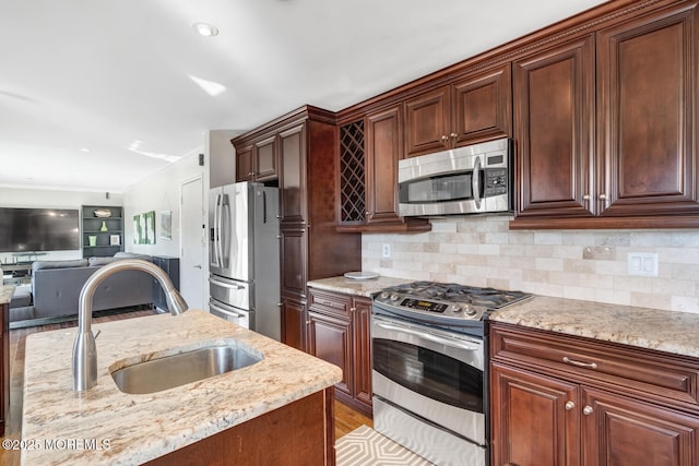 kitchen featuring stainless steel appliances, light stone countertops, sink, and decorative backsplash