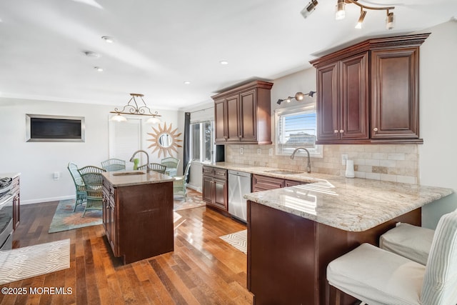 kitchen with dark wood-type flooring, tasteful backsplash, decorative light fixtures, stainless steel dishwasher, and kitchen peninsula