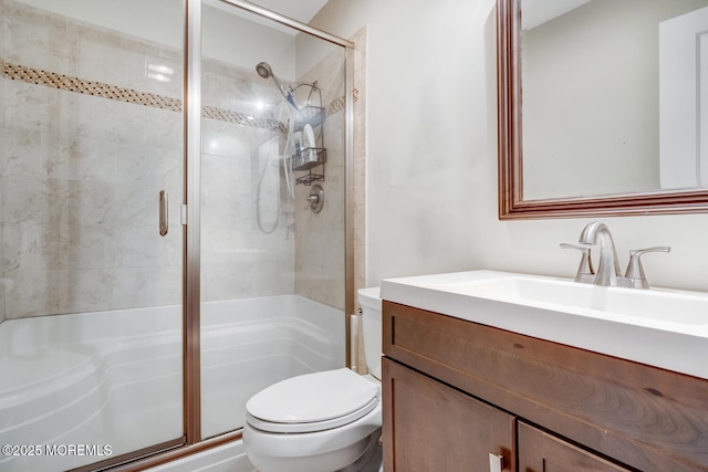 bathroom with toilet, vanity, and a shower with shower door