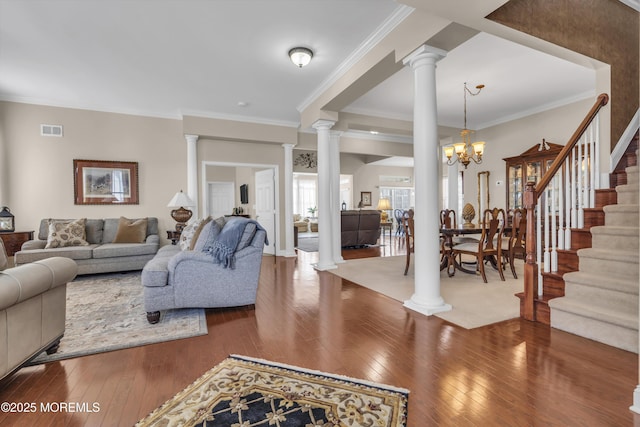 living room featuring hardwood / wood-style flooring, a notable chandelier, ornamental molding, and ornate columns