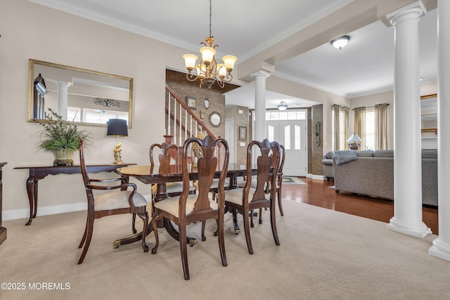 carpeted dining area featuring a notable chandelier, ornamental molding, and ornate columns