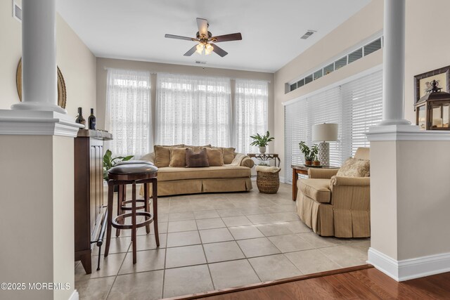 tiled living room featuring ceiling fan and ornate columns