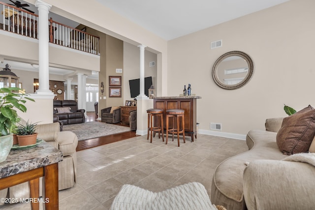 living room featuring decorative columns and light tile patterned floors