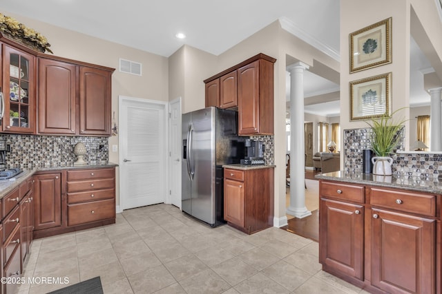 kitchen with stainless steel fridge, decorative columns, decorative backsplash, and dark stone countertops