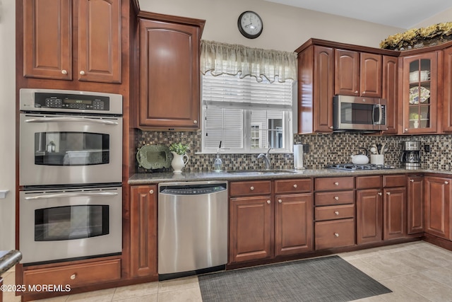 kitchen featuring stainless steel appliances, tasteful backsplash, sink, and light tile patterned floors