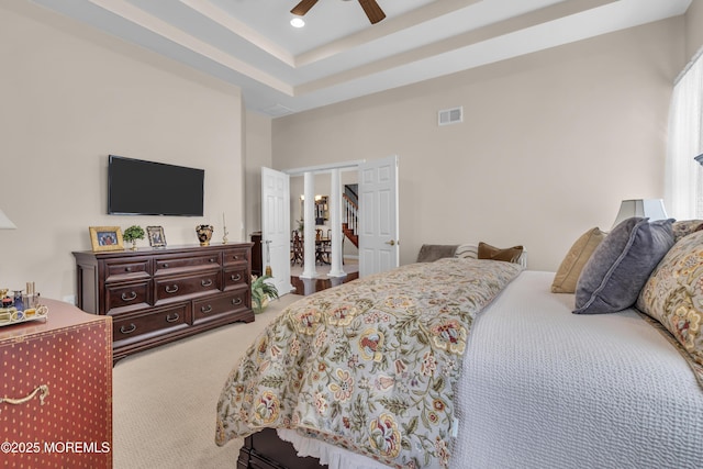 carpeted bedroom with a raised ceiling and ceiling fan