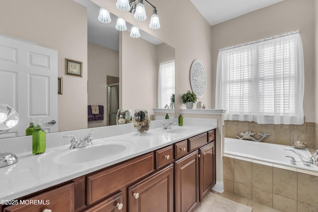 bathroom with tile patterned flooring, vanity, and tiled bath