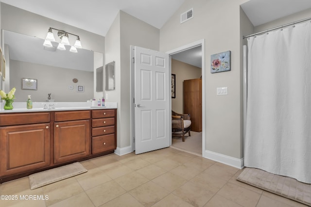 bathroom with tile patterned floors, lofted ceiling, and vanity