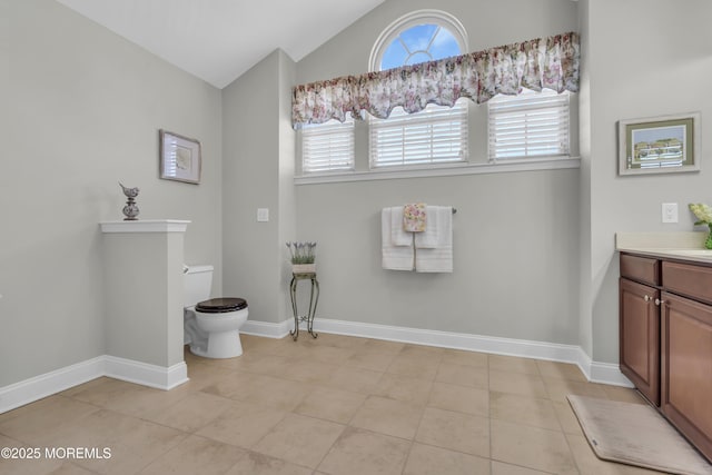 bathroom featuring tile patterned flooring, lofted ceiling, a healthy amount of sunlight, and toilet