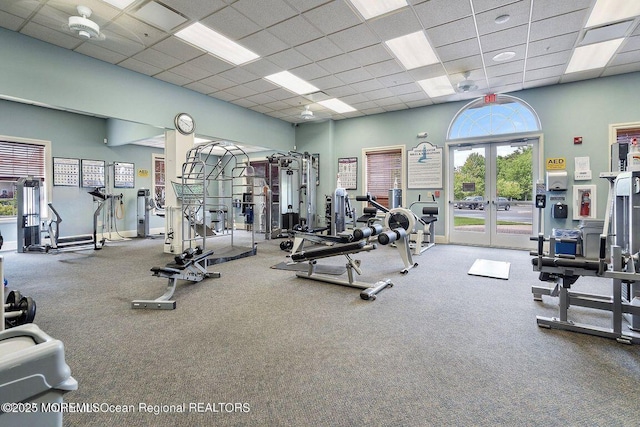 exercise room featuring a drop ceiling, a towering ceiling, and french doors