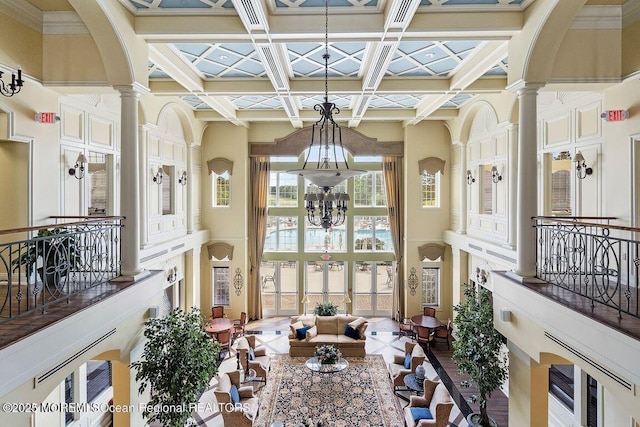 tiled dining area featuring coffered ceiling, ornate columns, a chandelier, beam ceiling, and a high ceiling