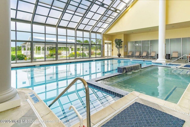 view of pool with pool water feature and glass enclosure