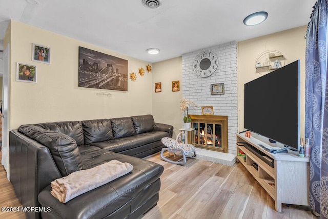 living room with light hardwood / wood-style floors and a brick fireplace