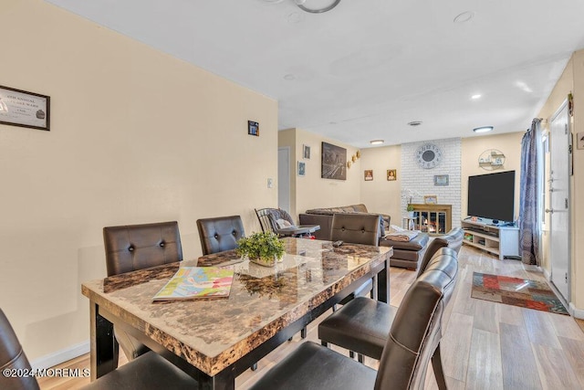 dining room featuring a fireplace and light hardwood / wood-style flooring